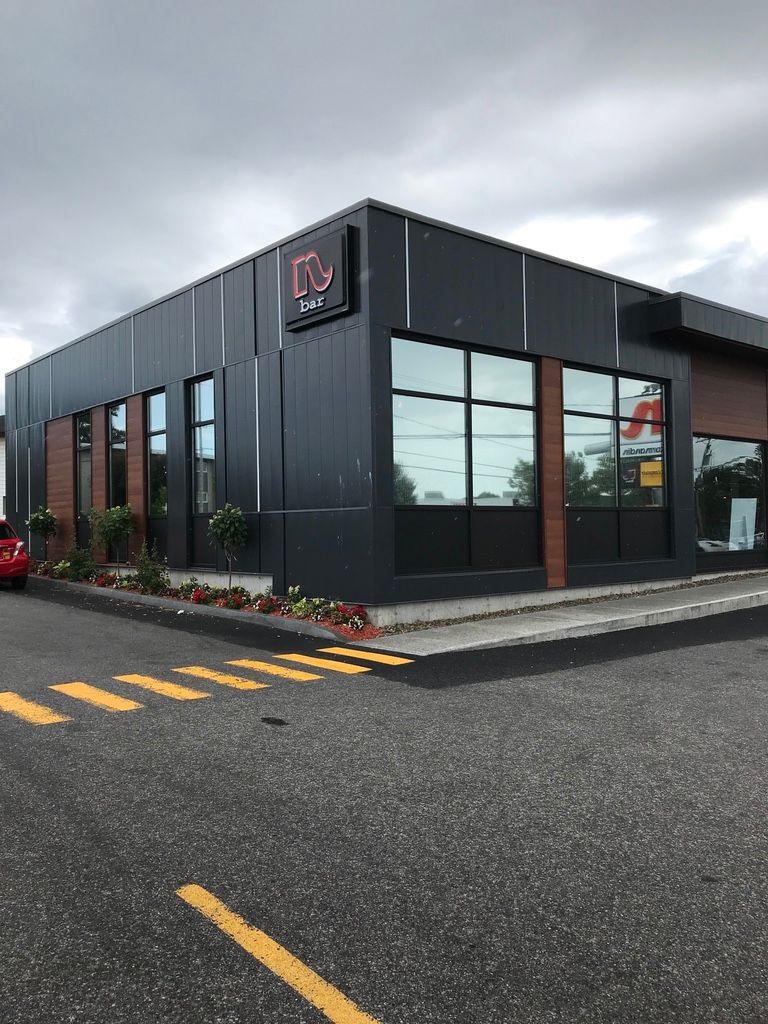Un grand bâtiment avec beaucoup de fenêtres et une voiture rouge garée devant.