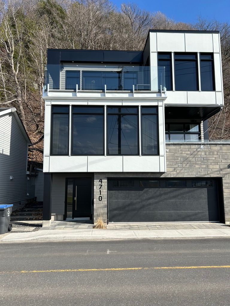 Une grande maison avec beaucoup de fenêtres est située au sommet d'une colline.