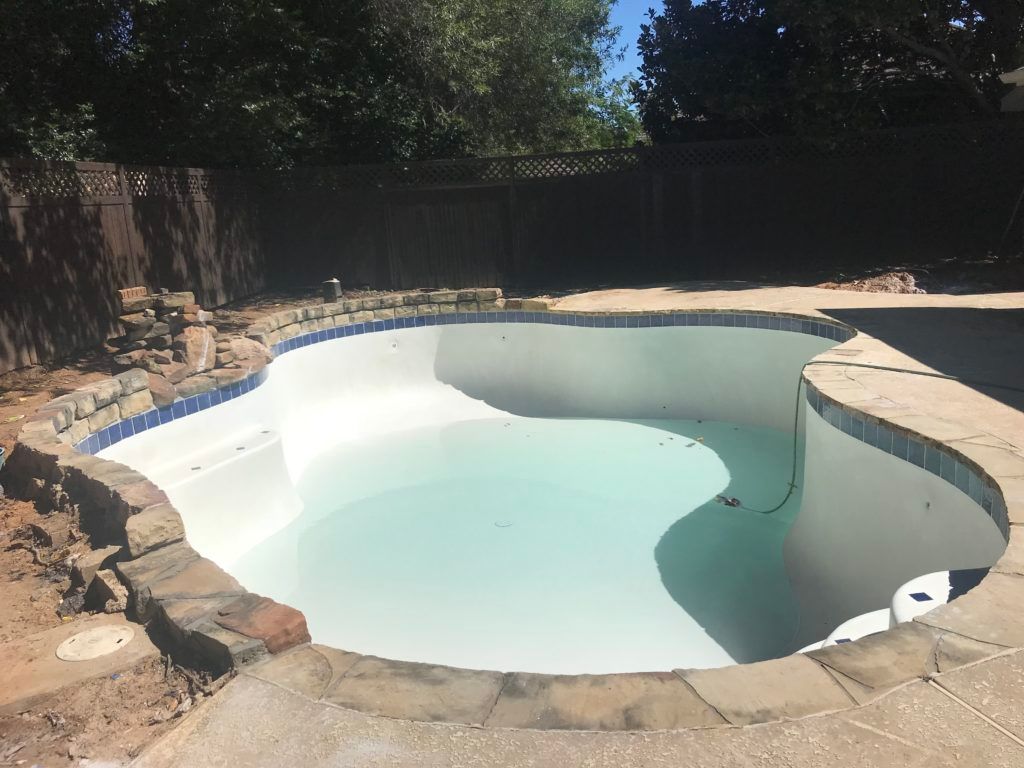 A large swimming pool with a fence in the background.