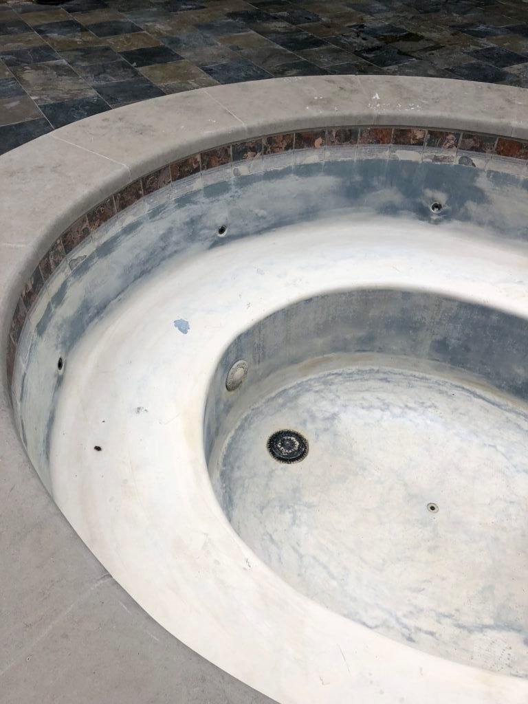 An empty hot tub with a drain in the middle of it.
