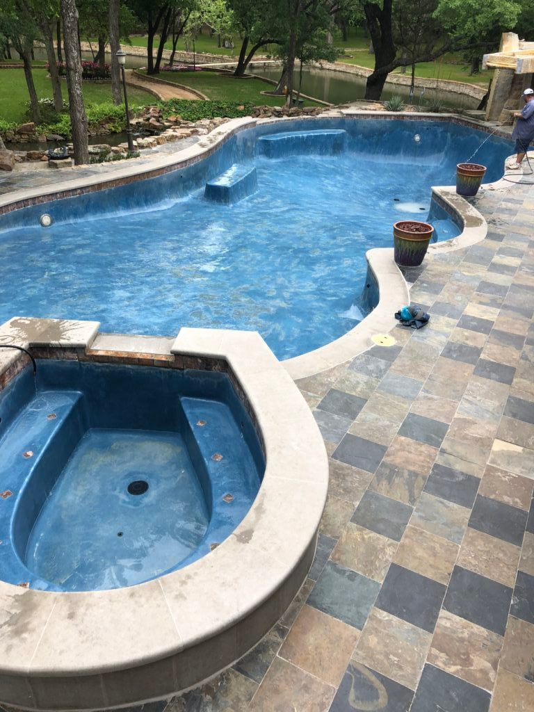 A large swimming pool with a hot tub next to it.