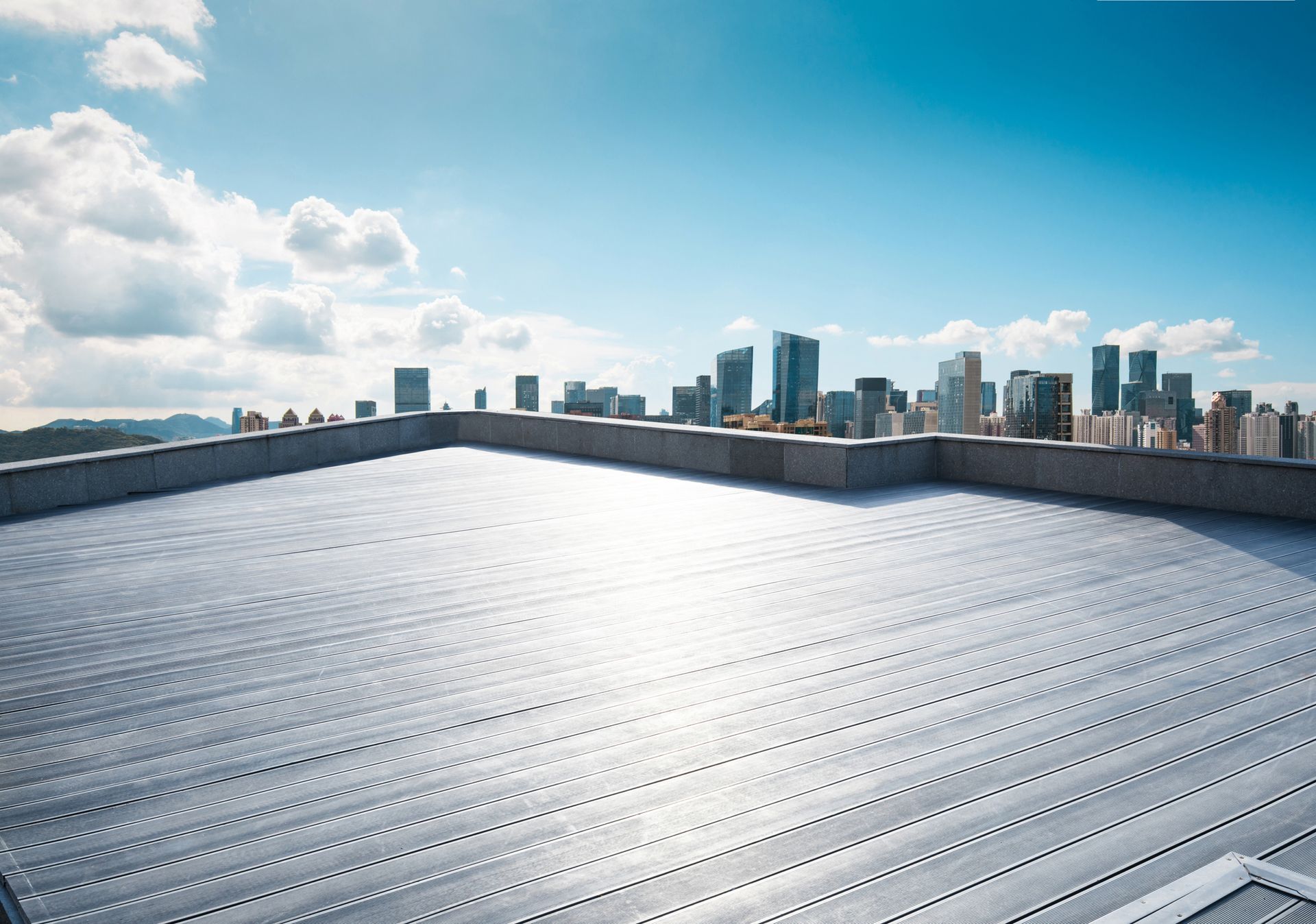 Rooftop overlooking a city skyline on a sunny day with a bright blue sky.