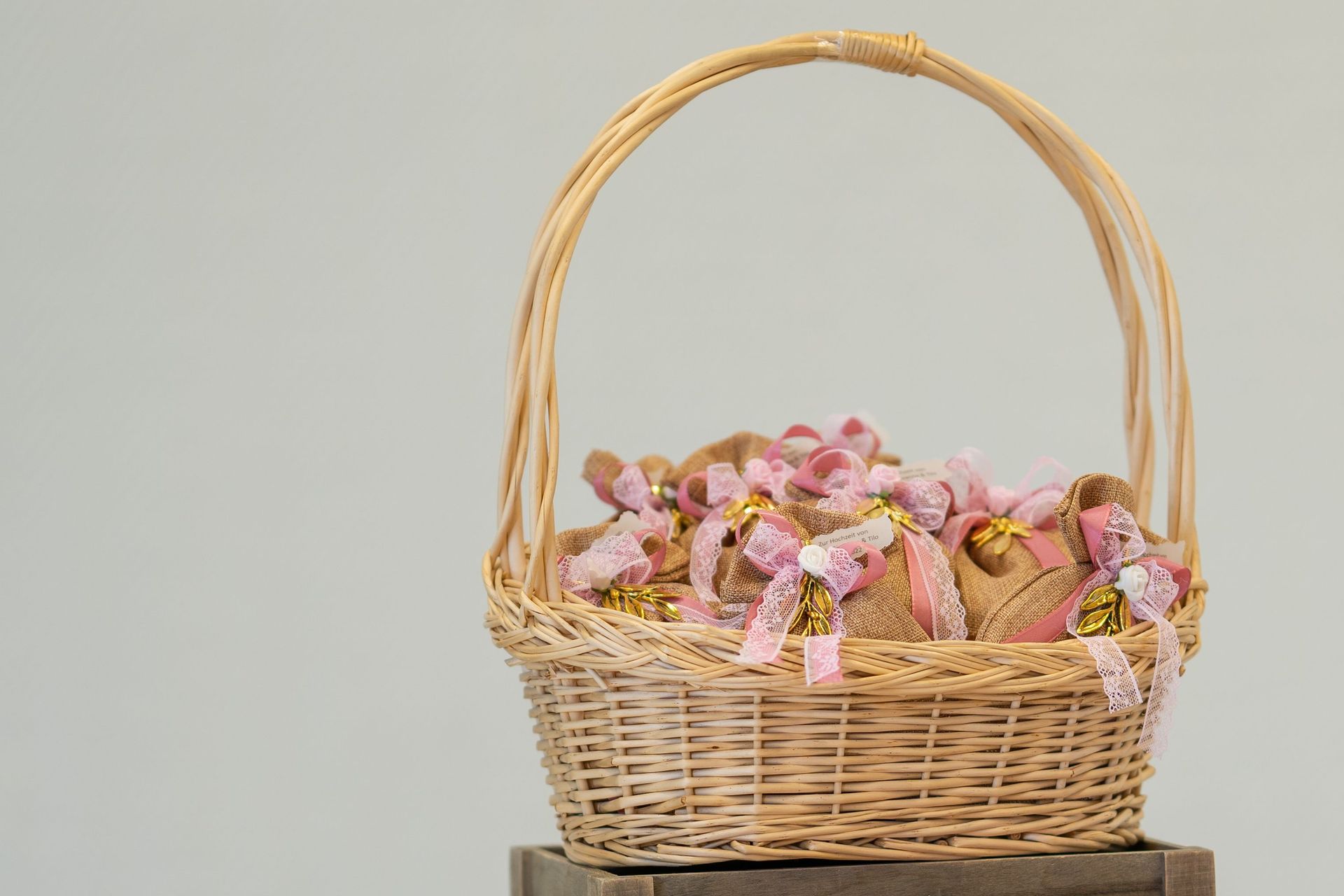 Wicker basket filled with pink flowers and ribbon on a wooden surface