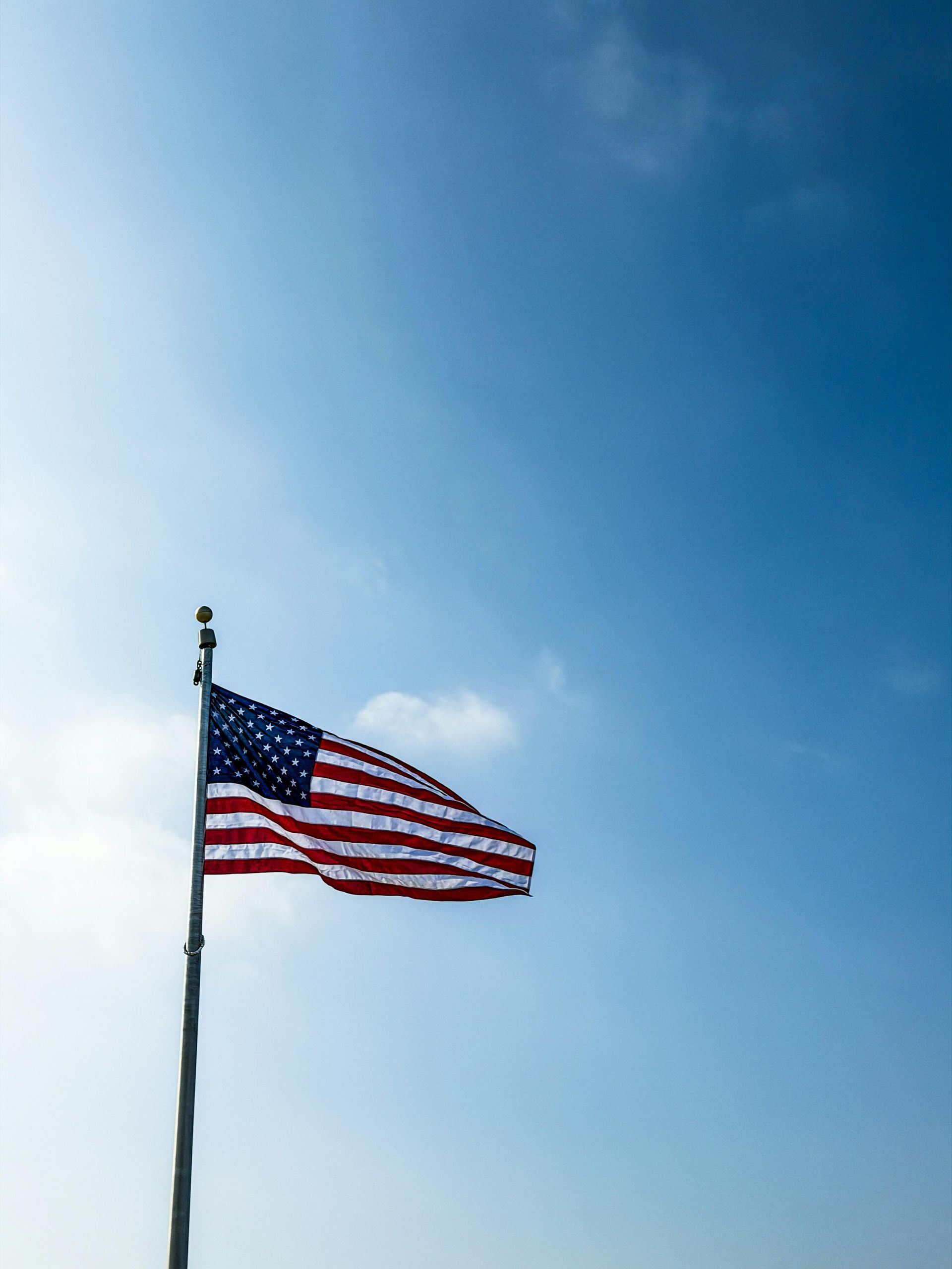 American flag waving on a pole against a blue sky