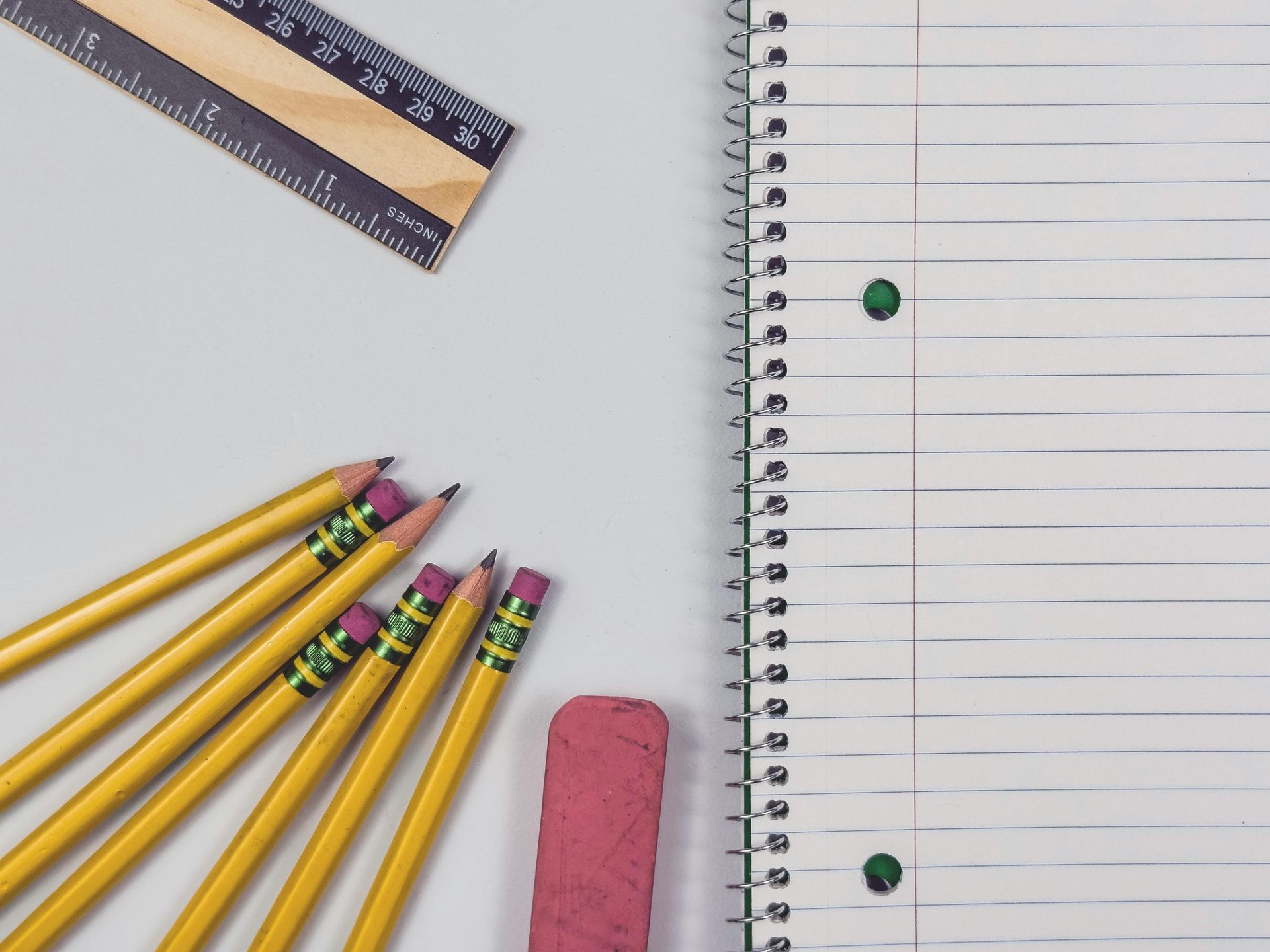 Pencils, ruler, eraser, and notebook on a desk with a blank lined page