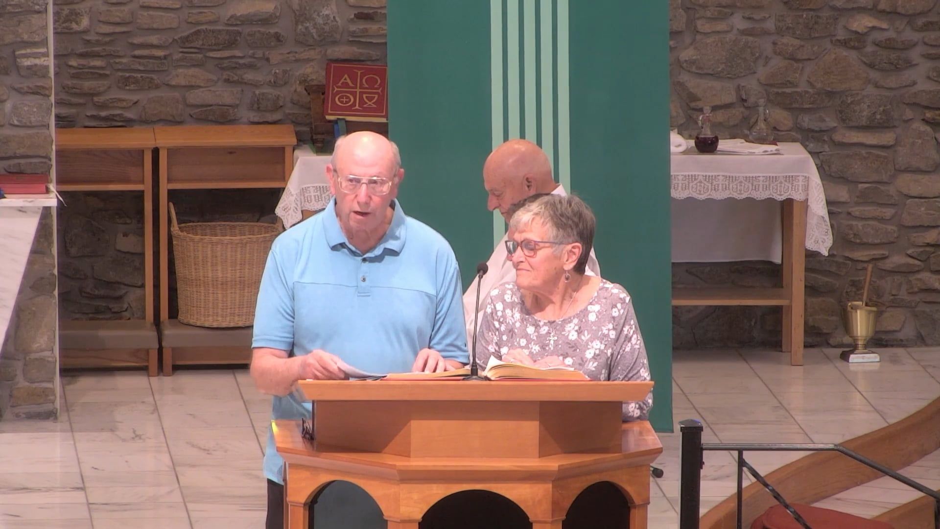 Man and woman speaking at a podium in a church setting.