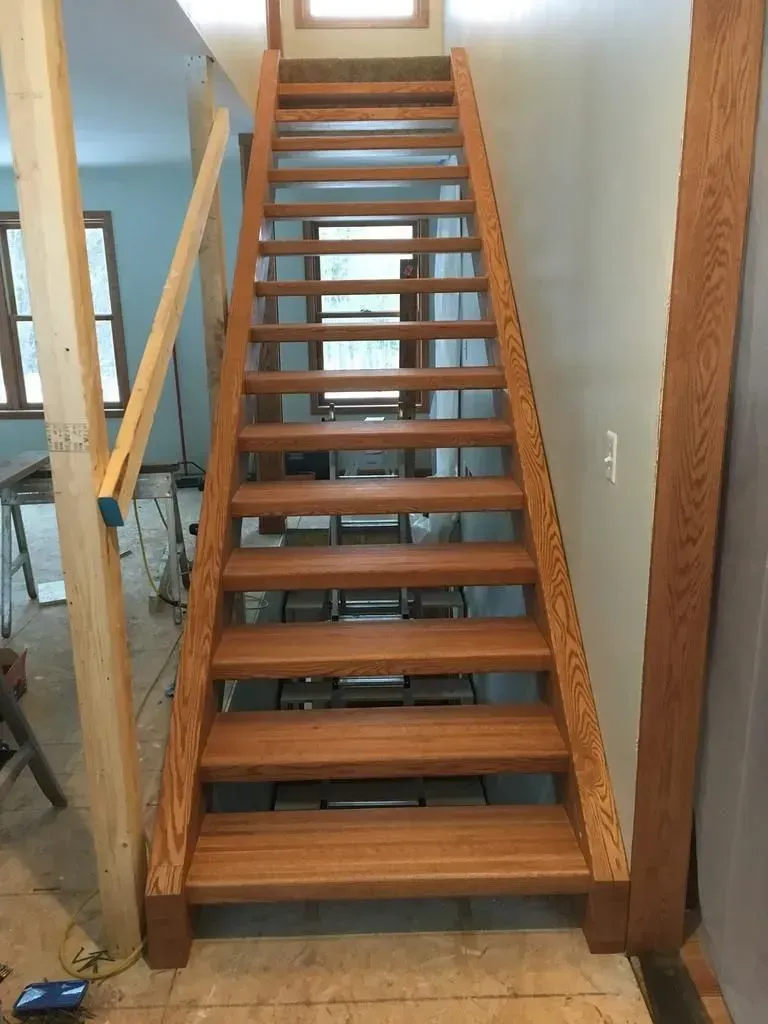 Wooden staircase leading to a loft with a window at the top inside a home.