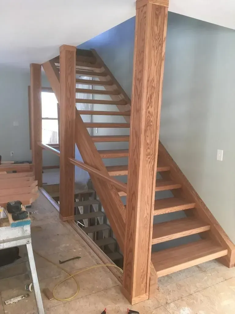 Wooden staircase with open risers and railings in an unfinished interior room