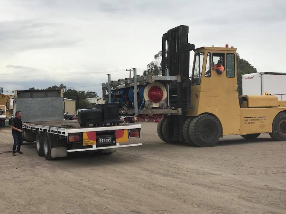 Yellow Forklift is Pulling a Flatbed Truck in a Dirt Lot — Pit Express in Tomago, NSW