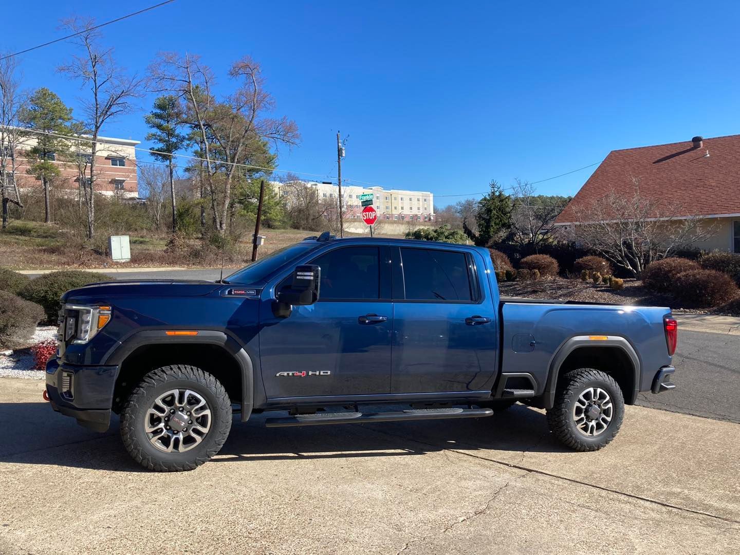 Blue GMC truck parked on a sunny day in front of buildings.