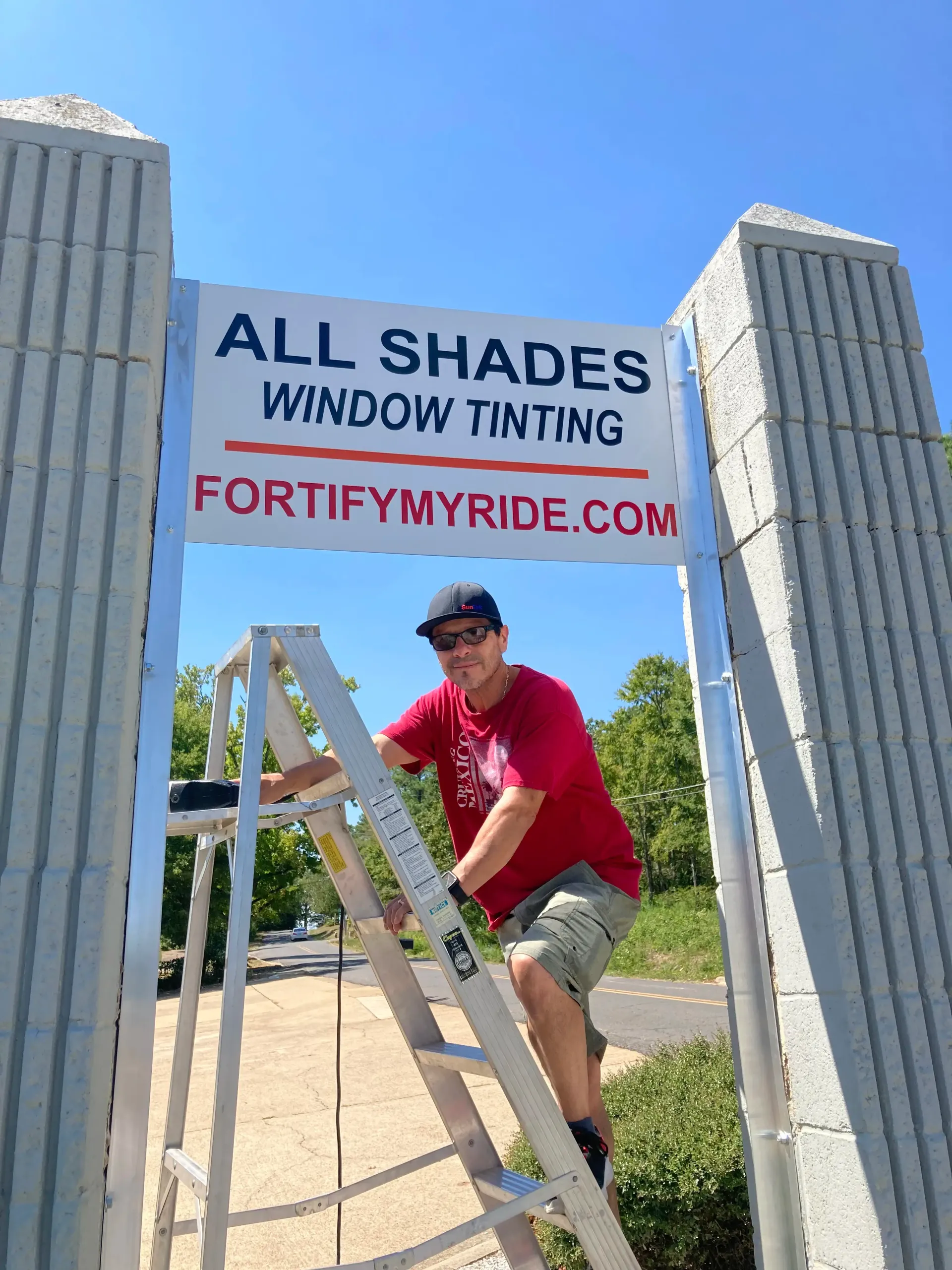 Man on a ladder installing a sign that reads