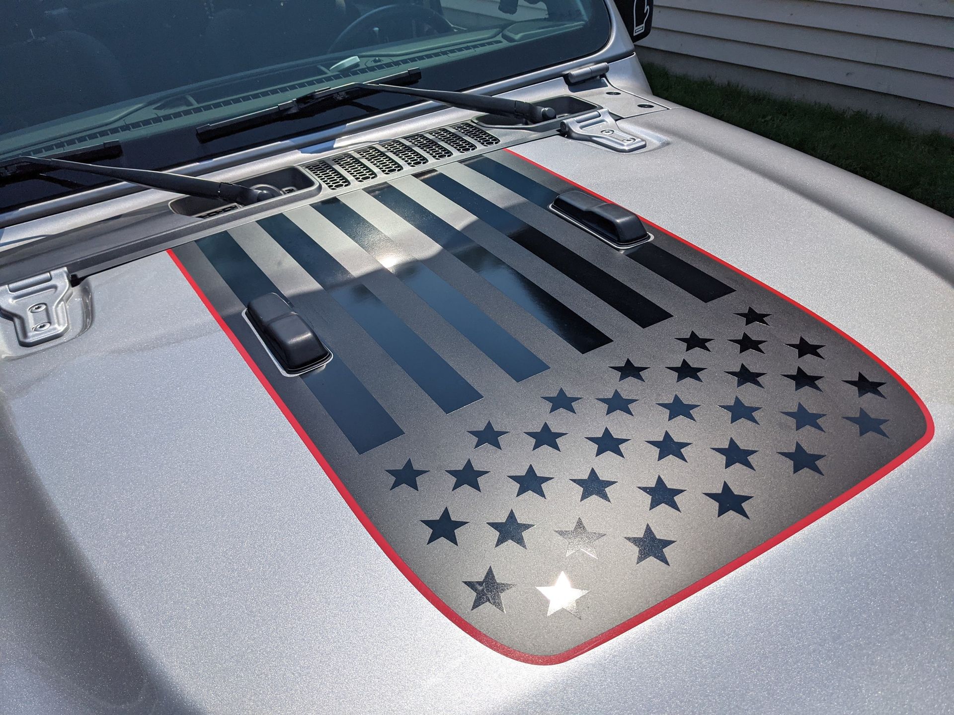 Silver Jeep hood with American flag design and red trim.