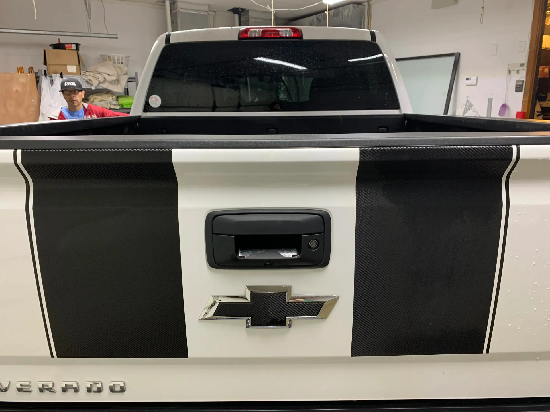 White Chevrolet Silverado truck rear with black stripe accents and logo.