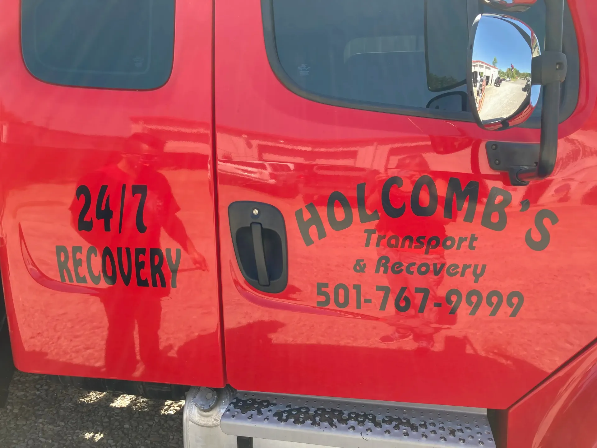 Red Holcomb's Transport & Recovery truck door with 24/7 Recovery service details and phone number.