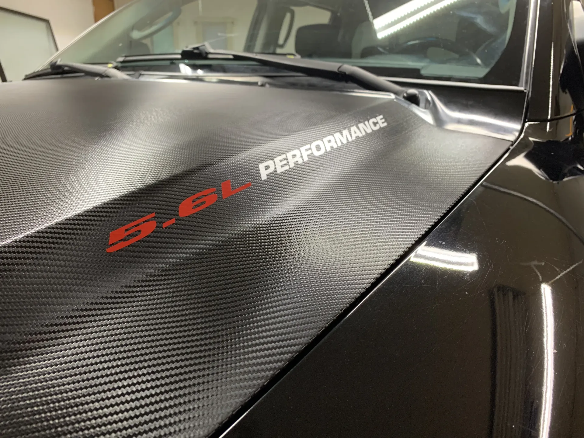 Black truck hood with carbon fiber wrap, red