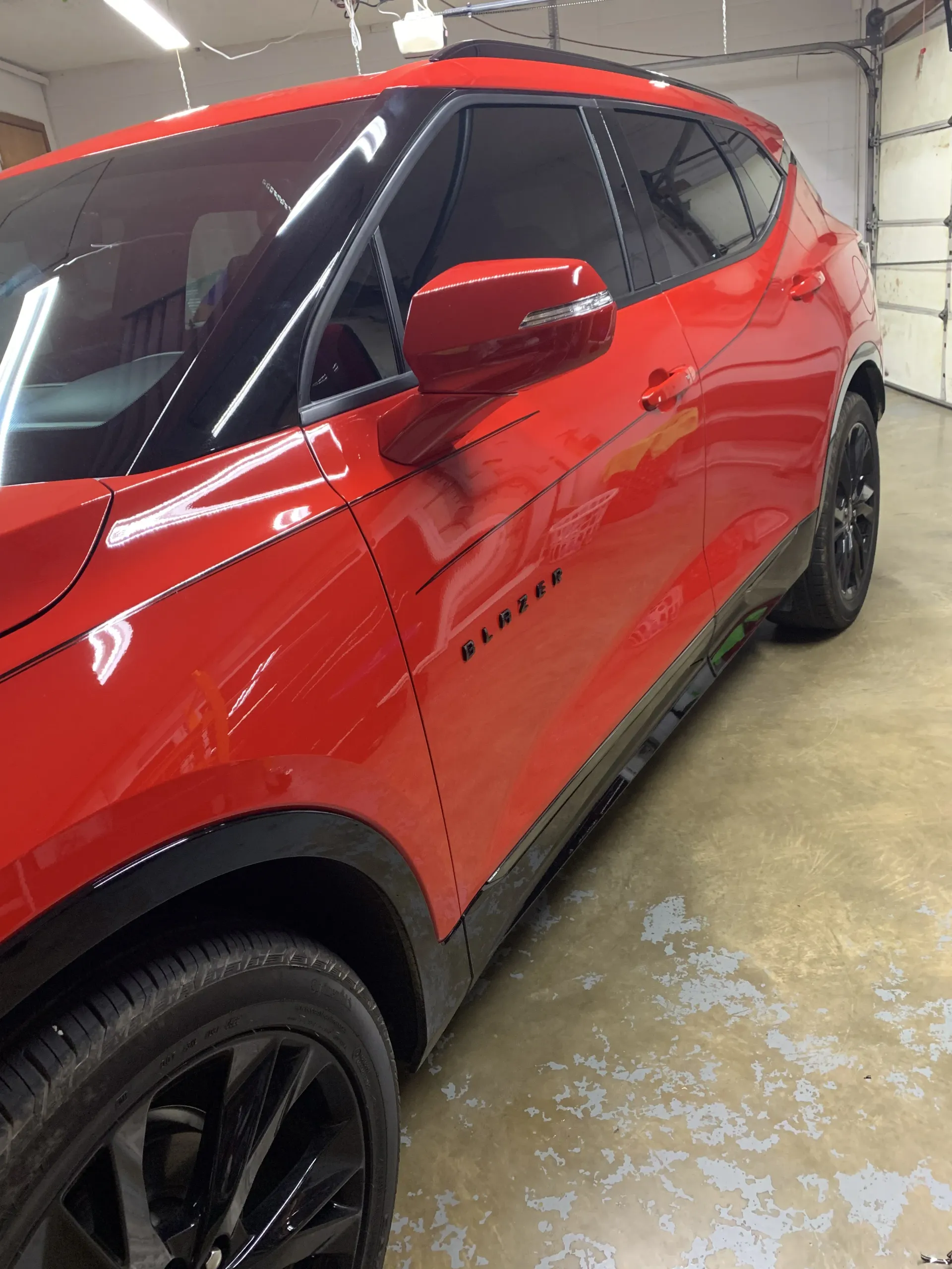 Bright red Chevrolet Blazer SUV with black wheels and tinted windows parked in a garage.
