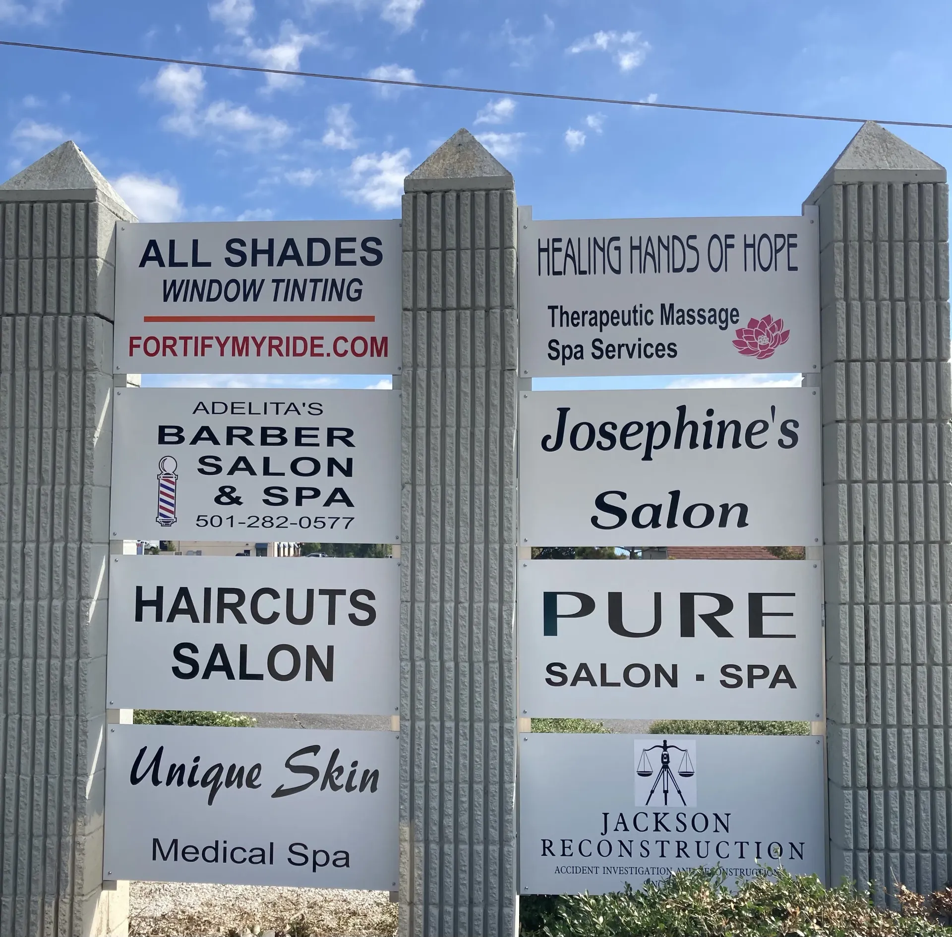 Signpost with various business names like salons, spas, and window tinting.