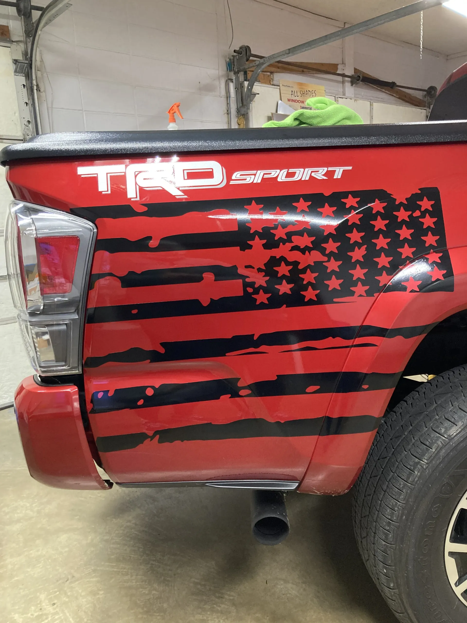 Red Toyota Tacoma truck with a black American flag decal on the side. The word