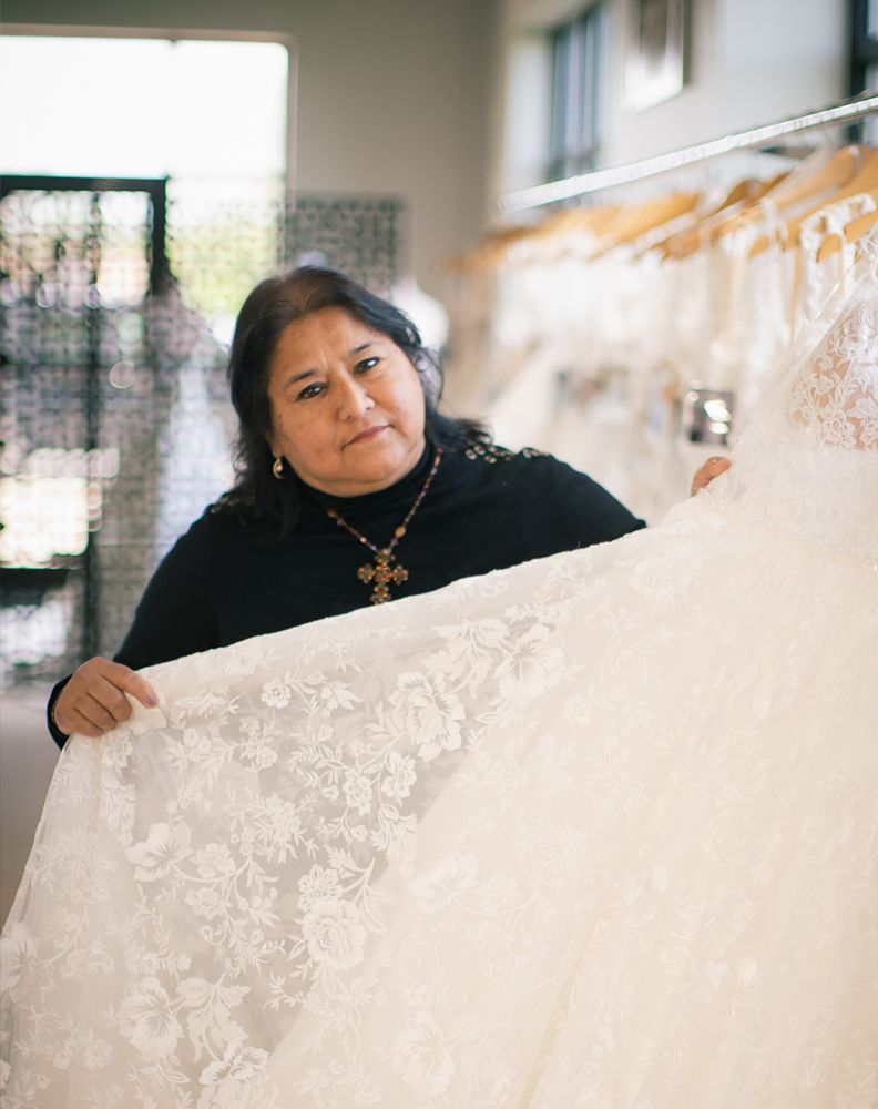 A woman is holding a piece of lace in a bridal shop.