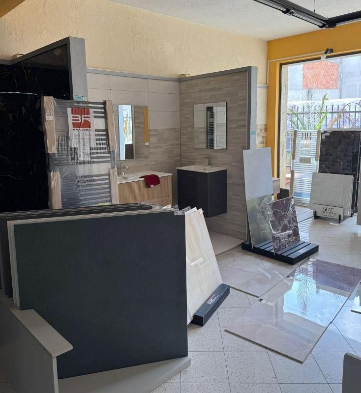 Interno dello showroom di piastrelle con bagno in esposizione e campioni di pietra impilati.