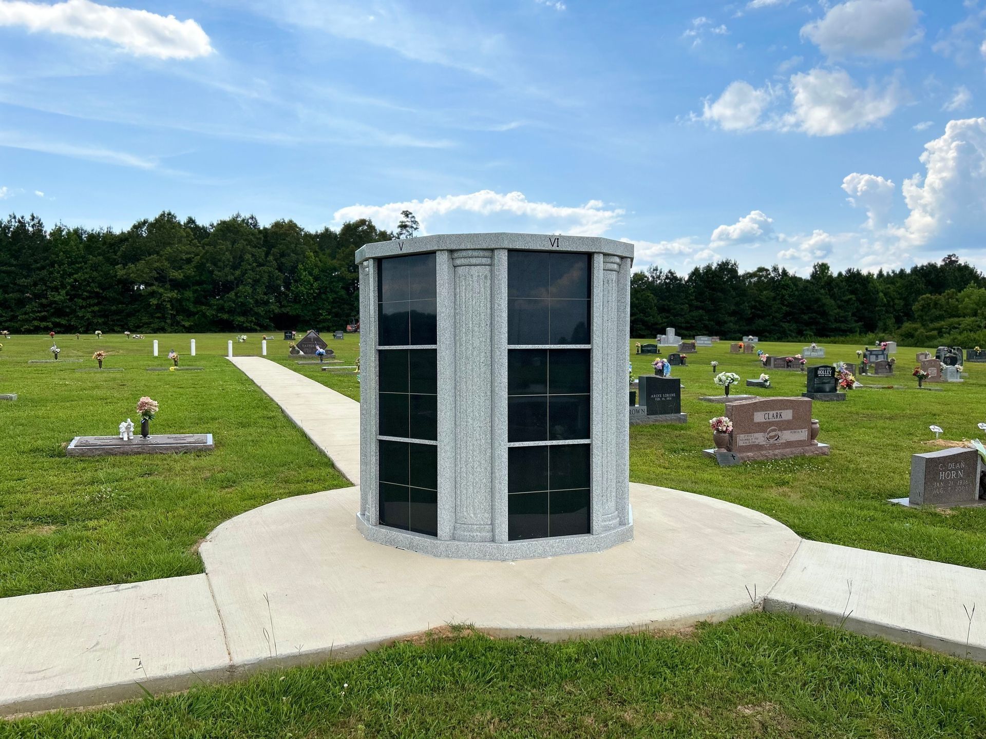 Cylindrical memorial columbarium in a grassy cemetery under a blue sky