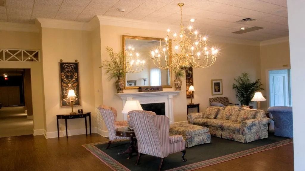 Elegant living room with chandelier, fireplace, striped chairs, floral sofa, and hardwood floors