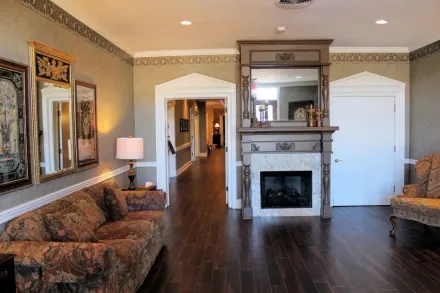 Spacious living room with hardwood floors, fireplace, sofa, lamps, and framed art on the walls