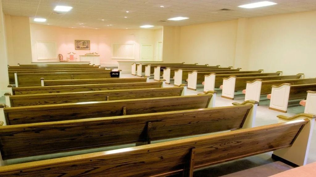Empty church sanctuary with wooden pews facing a bright altar and podium
