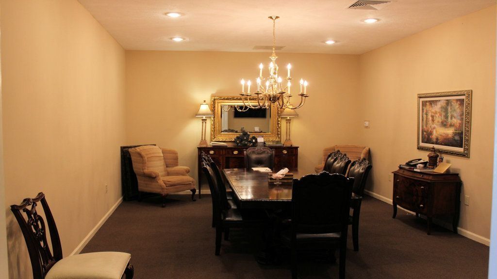 Elegant dining room with a long dark table, chandelier, beige walls, and framed artwork