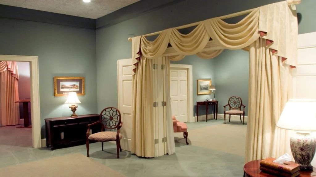 Elegant bedroom with cream drapery, teal walls, and antique furniture