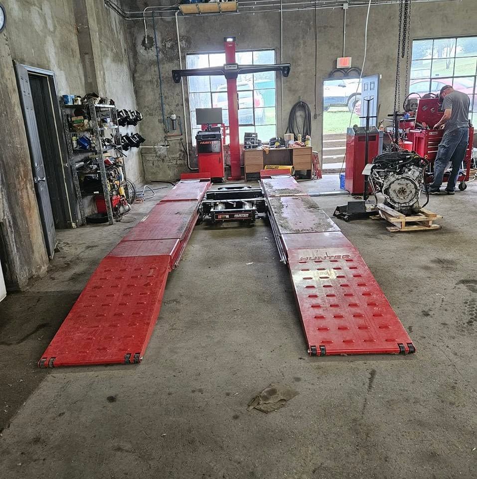 Auto repair shop with a car lift and red ramps, engine on the right, tools and equipment in the background