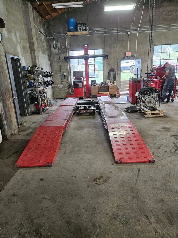 Auto repair shop with red ramps, a car lift in the center, and tools along the walls