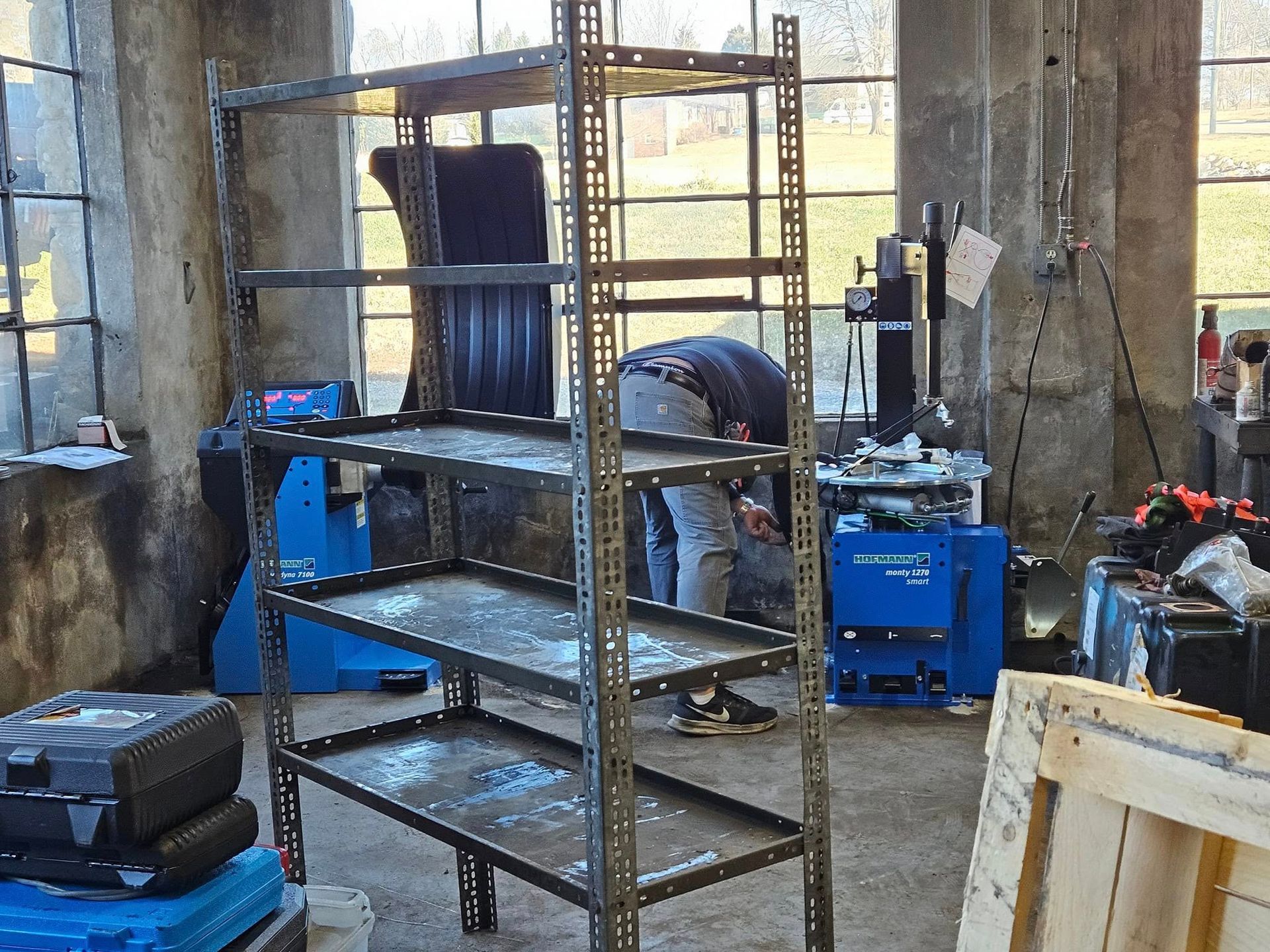 Industrial workshop with metal shelving and blue equipment inside a concrete building.