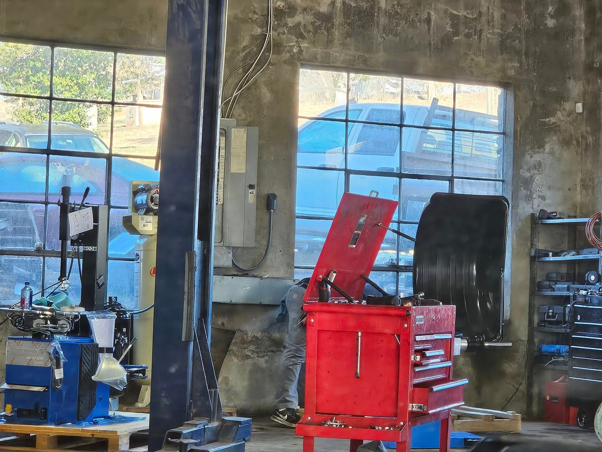 Auto shop with blue lift, red tool chest, and workbench in a concrete garage.