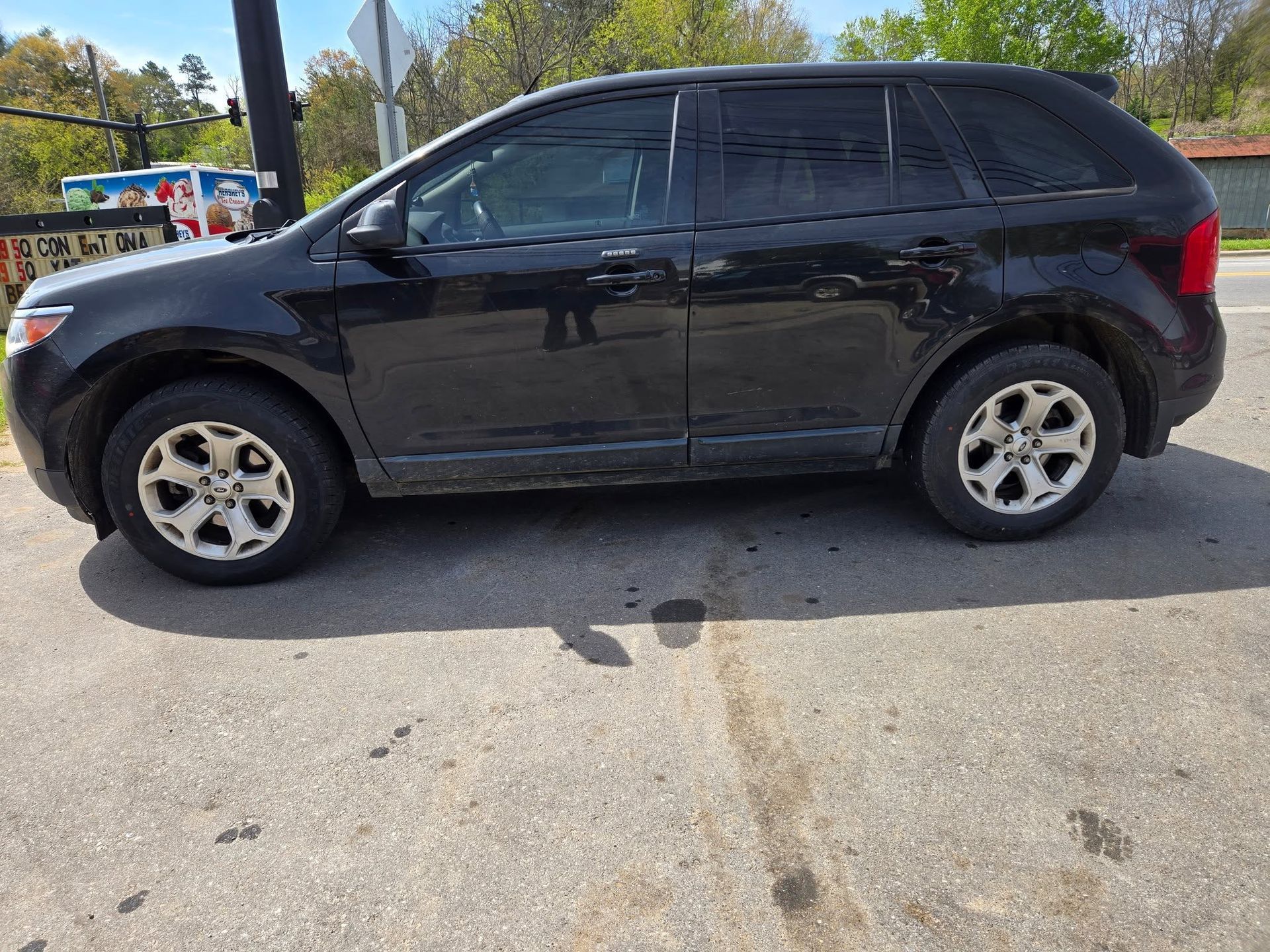 Black SUV parked on a sunlit paved lot