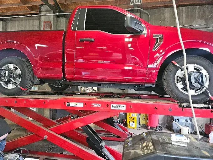 Red pickup truck on a hydraulic lift in an auto repair shop