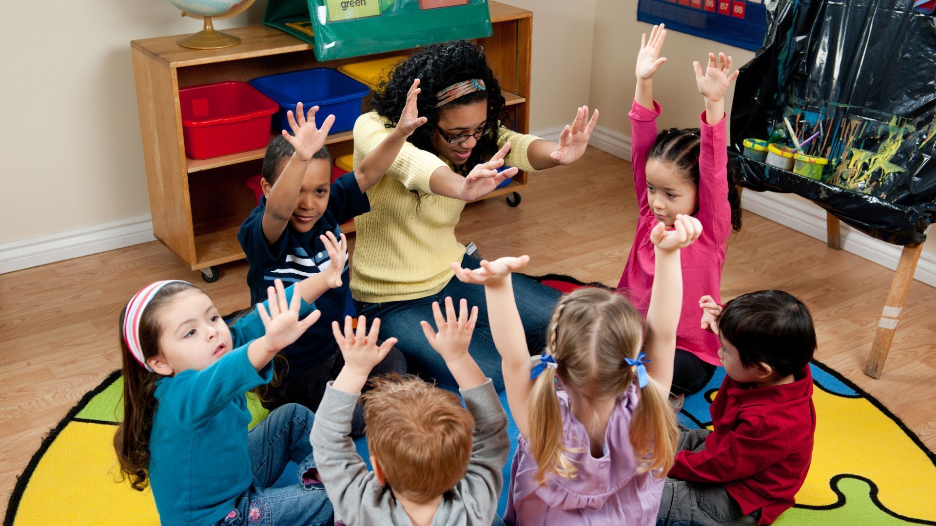 A group of children are laying on the floor and smiling for the camera.