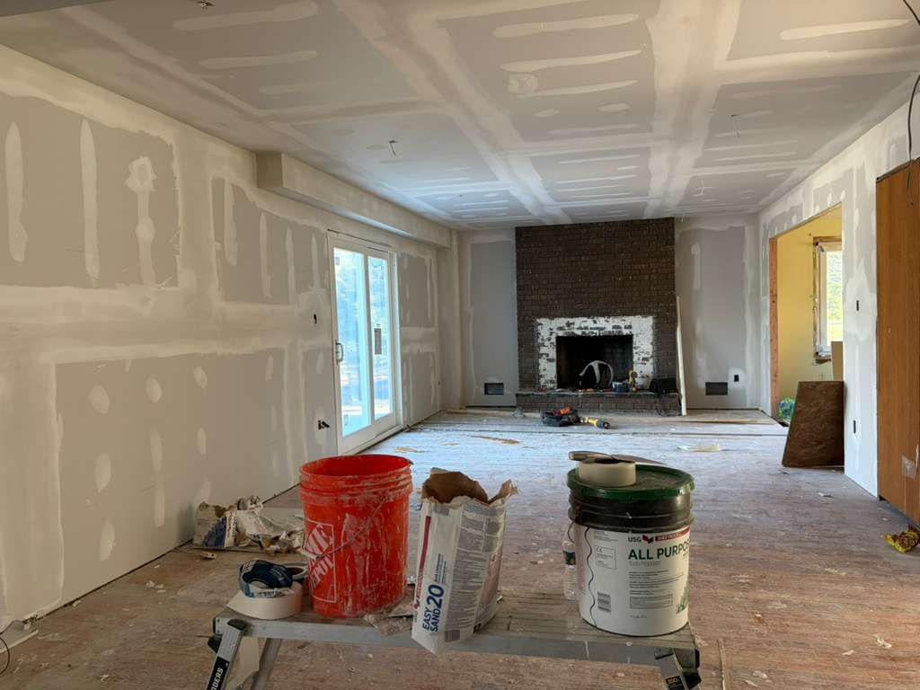 Interior of a home under construction featuring unfinished drywall, a fireplace, and supplies on a platform in the center.