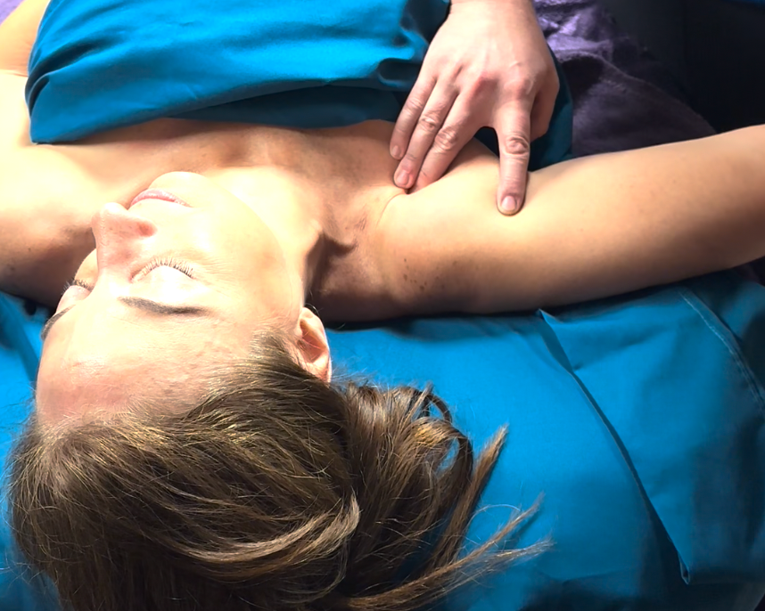 A woman is laying on a blue blanket and getting a massage