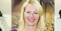 A woman with blonde hair is smiling in a shoe store.