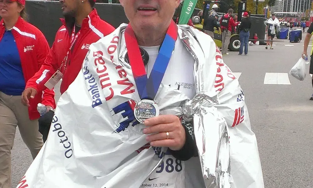 A man is holding a medal and wearing a blanket that says bank of america on it