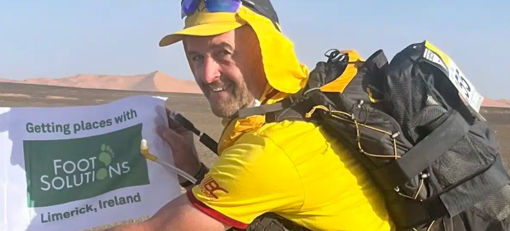 A man with a backpack is holding a sign that says getting places with foot solutions.