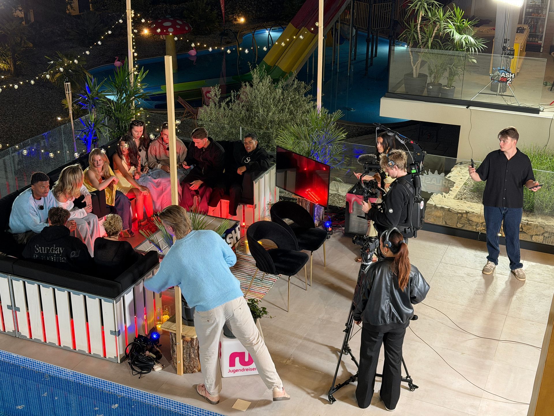 Outdoor-Abendset am Pool mit Creatorn auf Couch, Camera Operator mit Gimbal und Beleuchtung