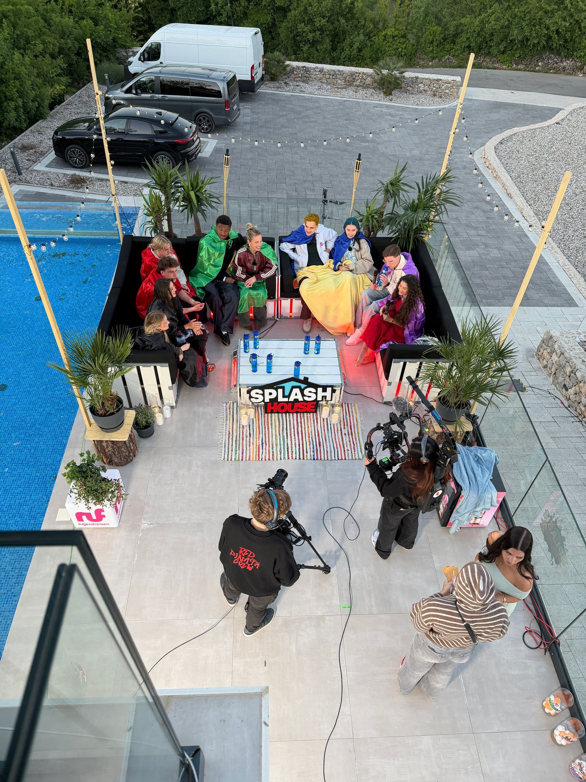 Top-Shot vom Outdoor-Abendset bei Nacht mit Creatorn, Lichterketten und Pool-Beleuchtung
