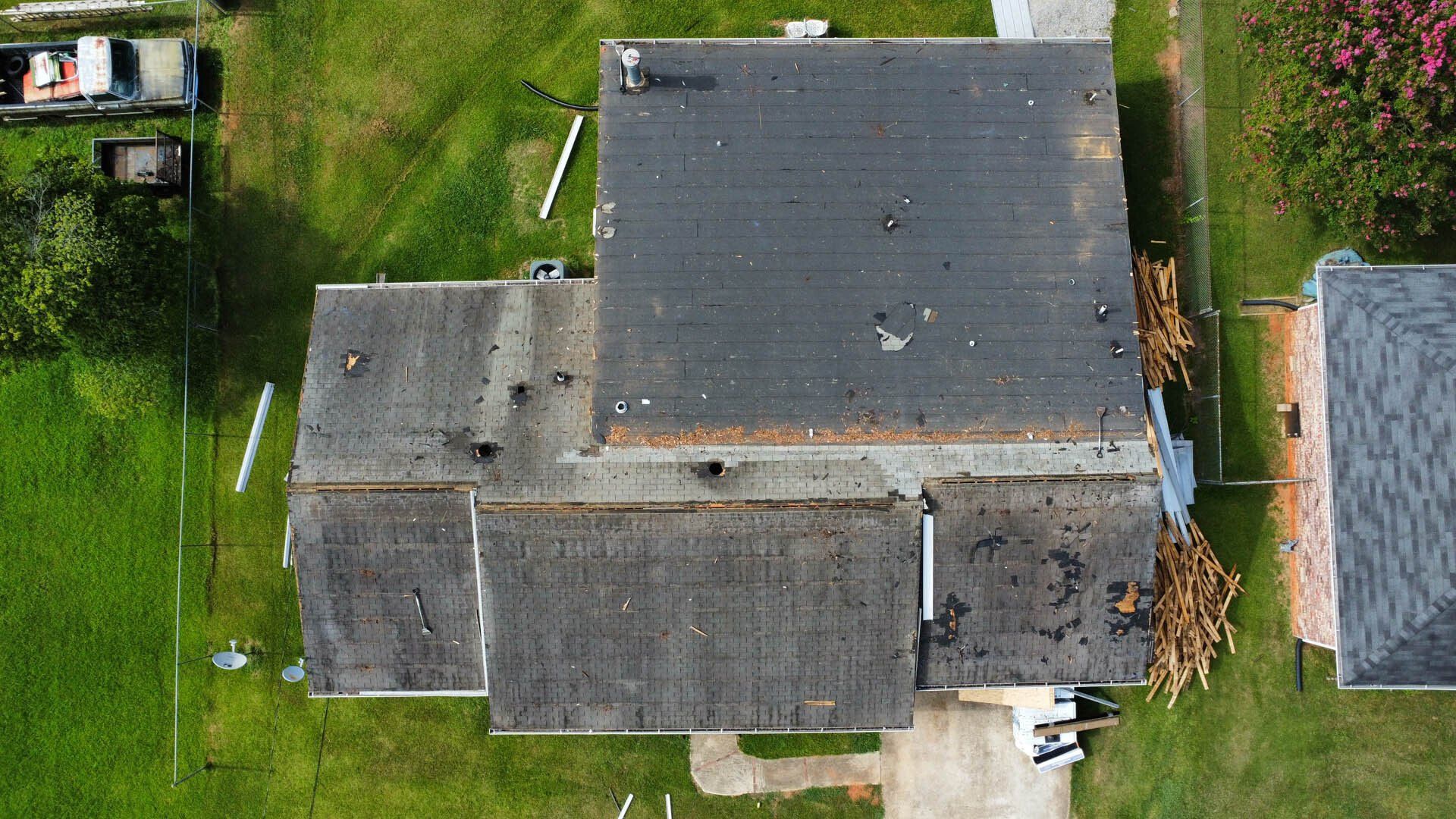 An aerial view of a house with a roof that is missing shingles.