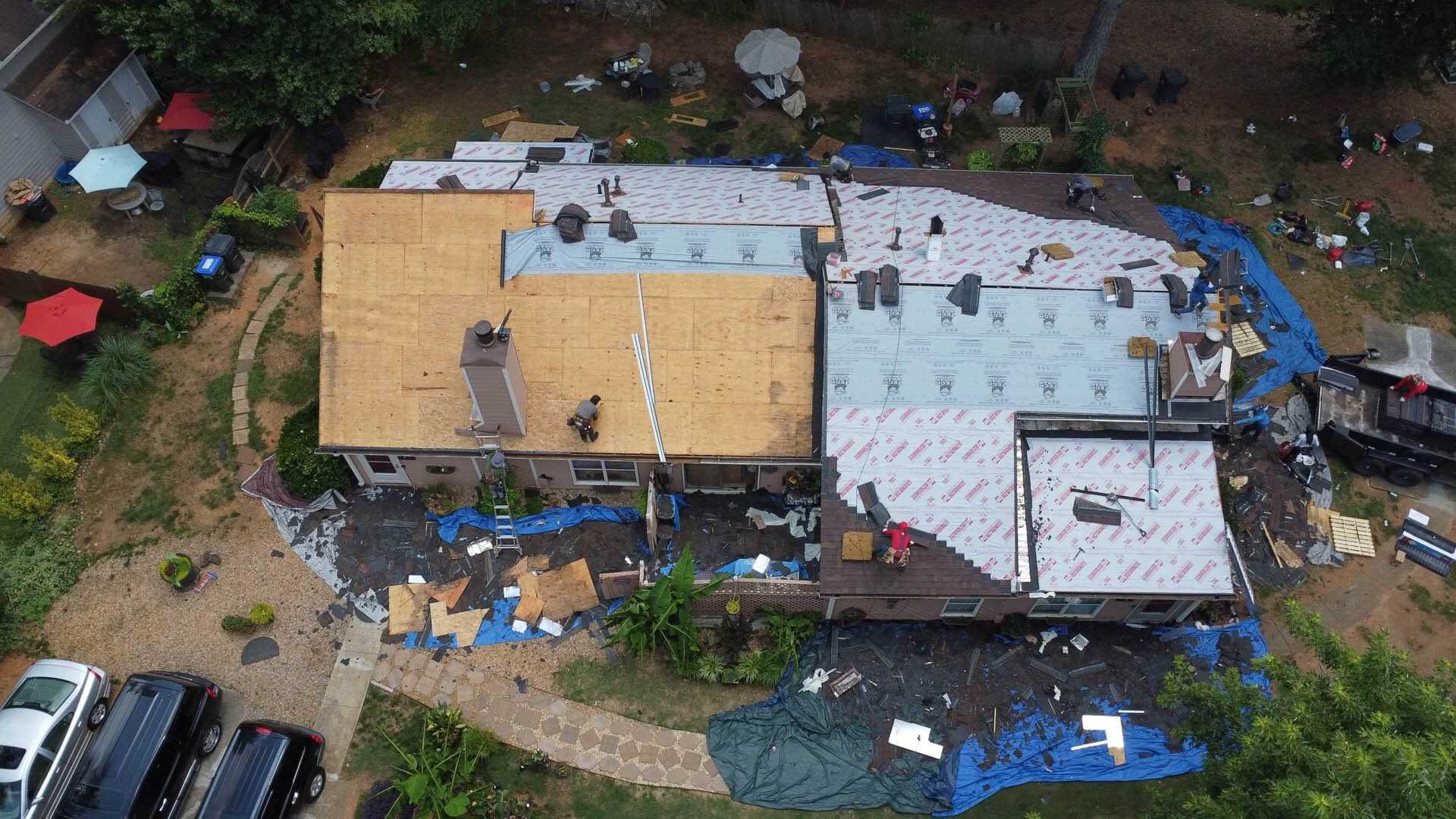 An aerial view of a house under construction with a roof being installed.