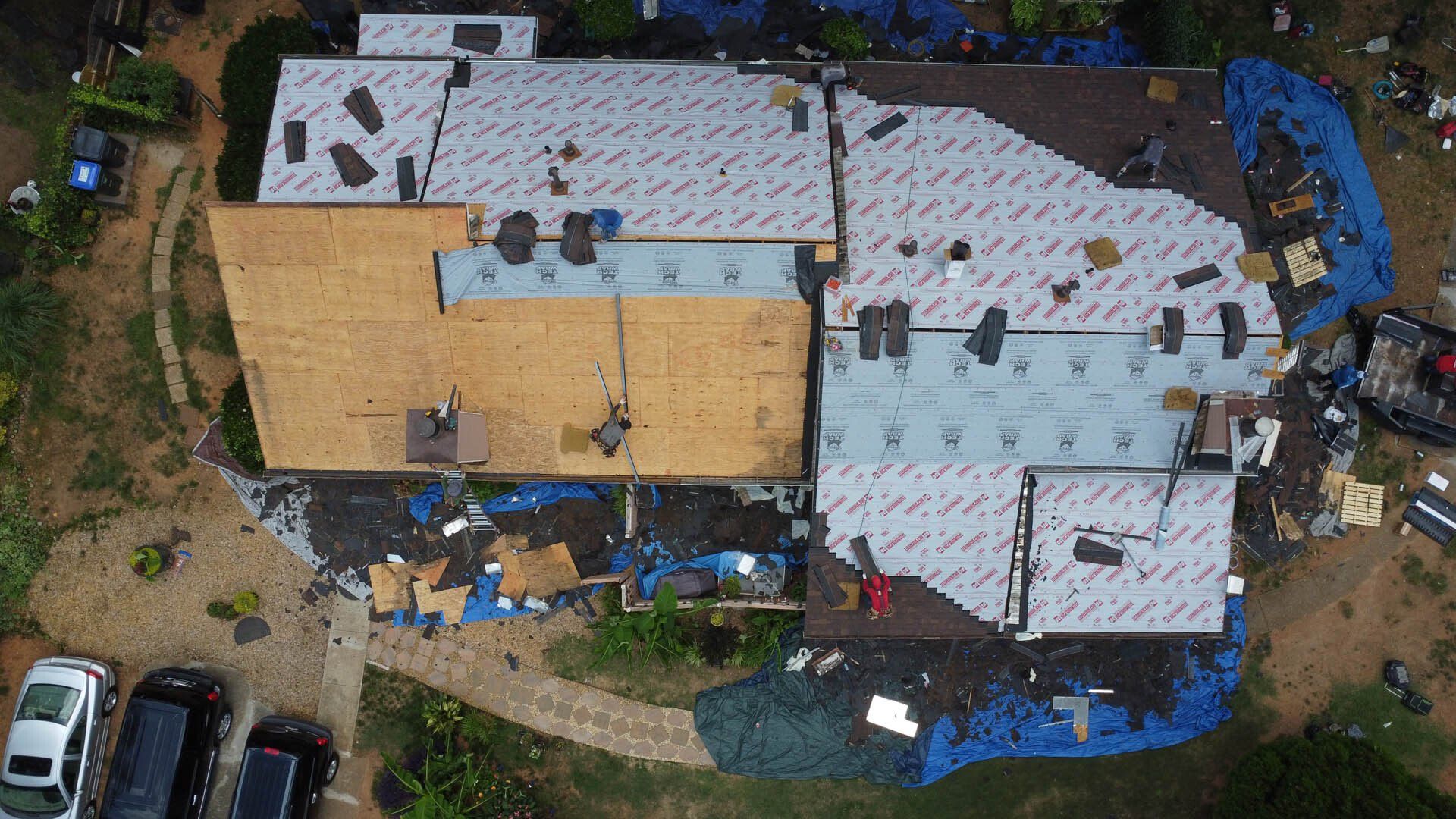 An aerial view of a house under construction with a roof being installed.