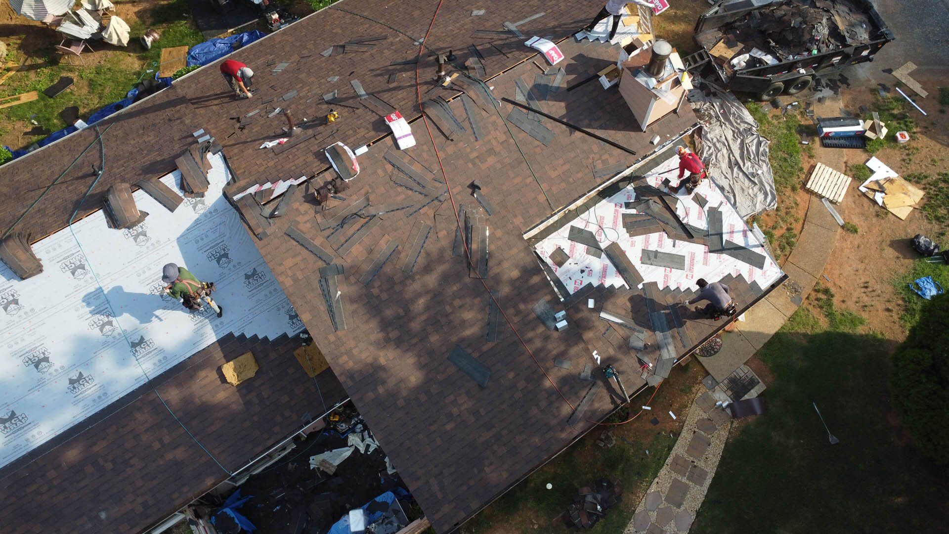 A group of people are working on the roof of a house.
