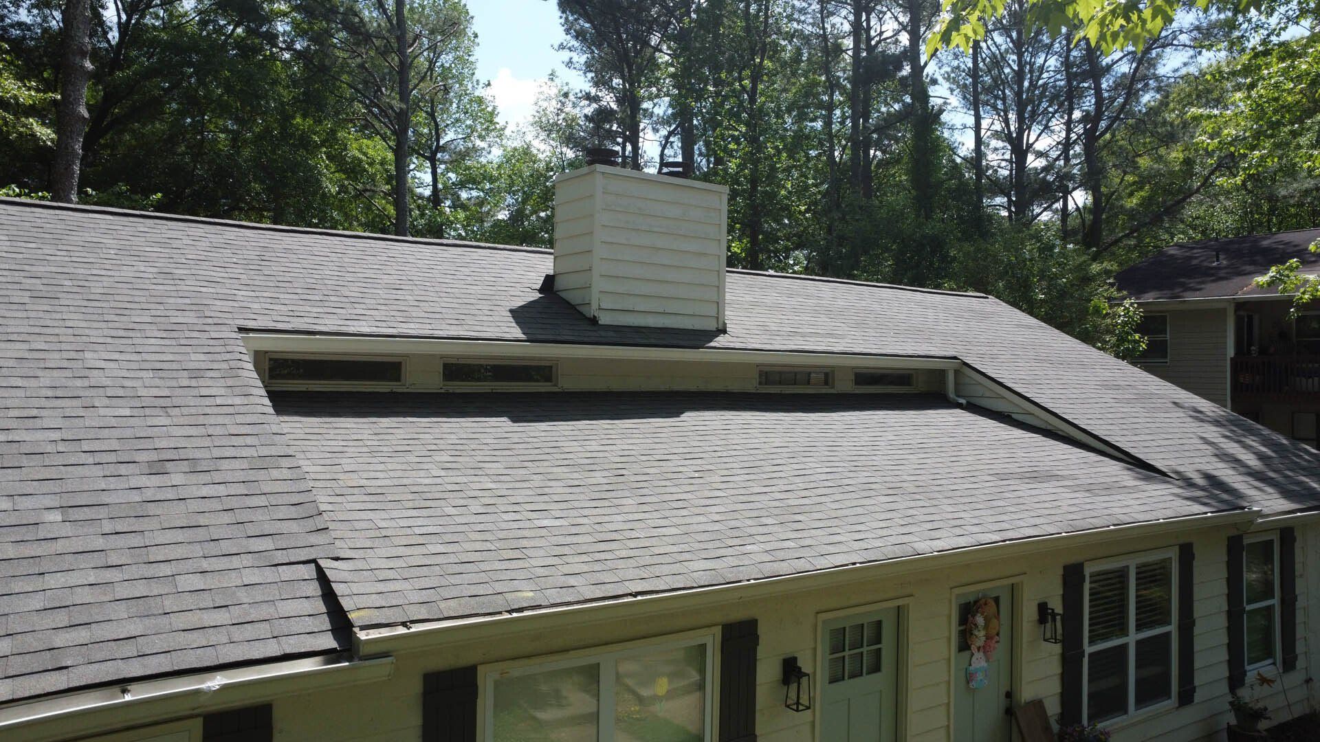 A house with a chimney on the roof and trees in the background.