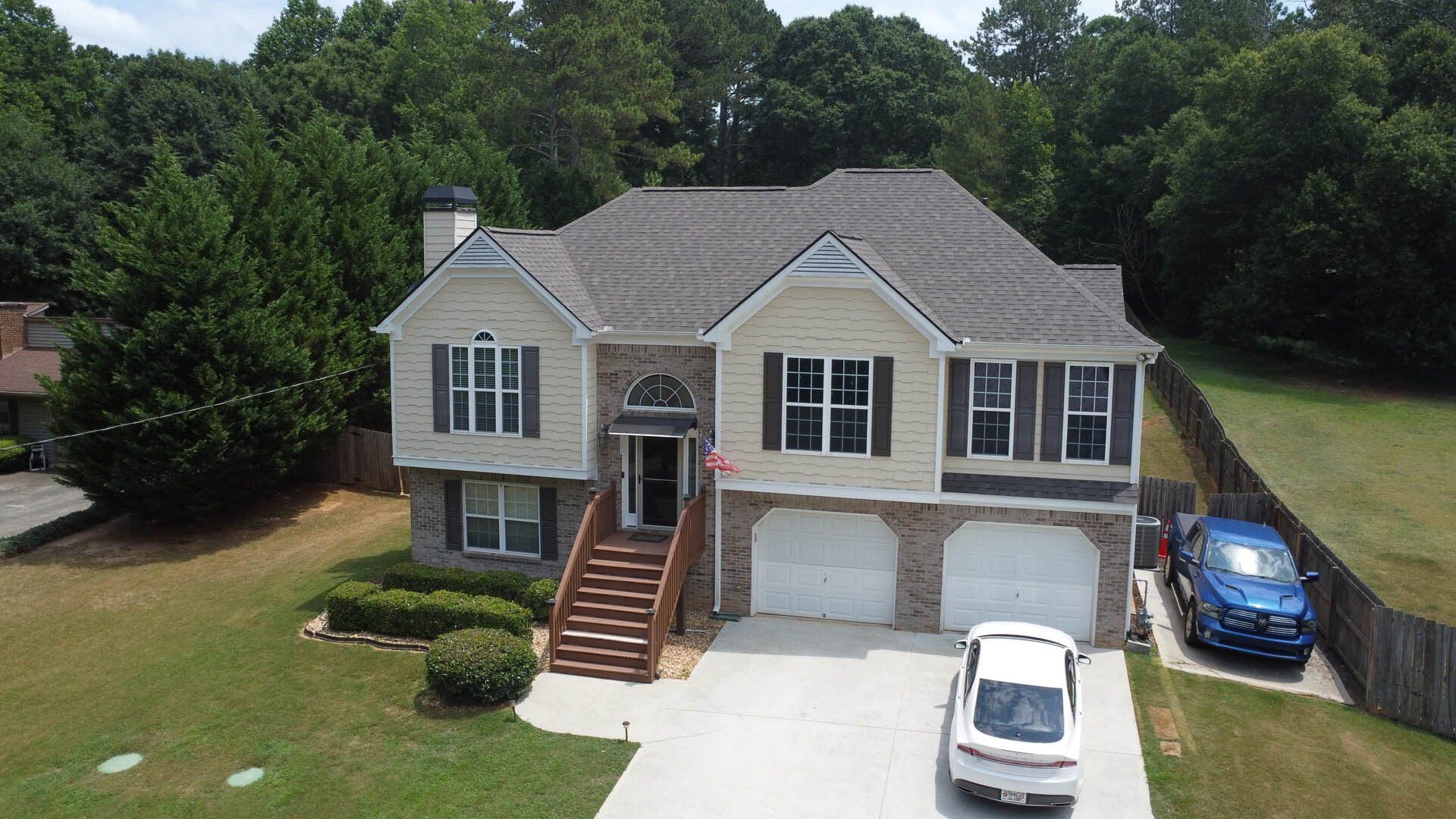 An aerial view of a large house with two cars parked in front of it.